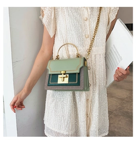 Detail of color-block handbag with gold chain strap and metal handle on a model