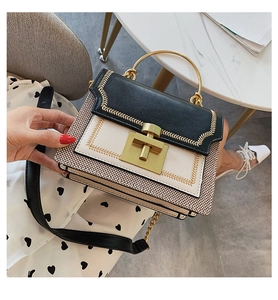 Detail of crossbody bag with gold leaf embroidery, metal handle and twist lock