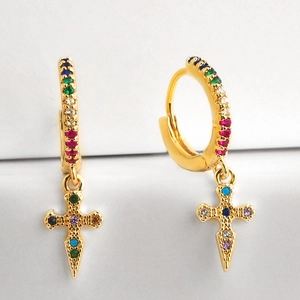 Macro shot of gold hoop earrings with colorful rainbow zircons and a cross pendant