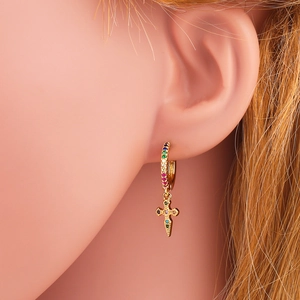 Close-up of golden cross hoop earring with colorful rhinestones on a female model