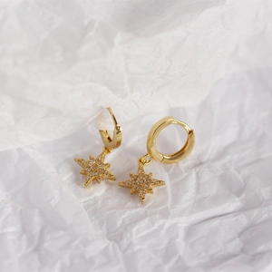 Macro shot of gold star hoop earrings with sparkling crystals on white paper background