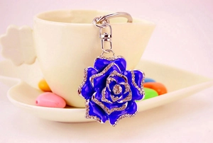 Close-up of royal blue rhinestone rose keychain hanging on a ceramic coffee cup