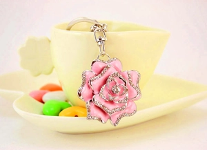 Detailed view of pink rose keychain with rhinestones and spring buckle on a cup