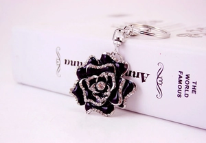 Macro detail of a black rose keychain with sparkling rhinestones on a white book