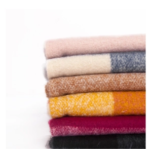 Stacked cozy plaid scarves in diverse colors like pink and orange with soft fringe detail