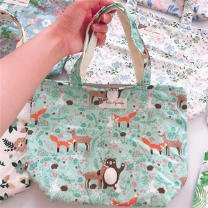 Detail of mint green canvas bag with cartoon animal patterns and top zipper closure