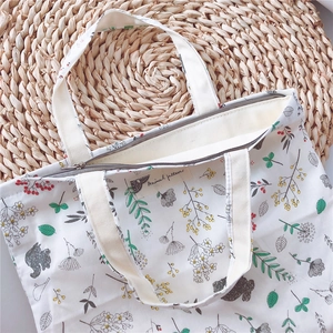 Detail of canvas tote bag showing top zipper closure and animal pattern embroidery