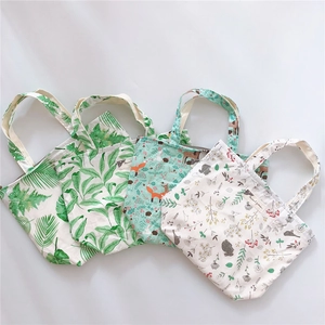 Detail view of cotton canvas tote bags featuring tropical leaf and floral patterns