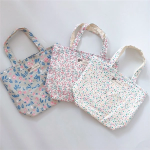 Close-up of three floral and polka dot cotton tote bags with animal pattern labels