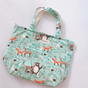 Detail of mint green canvas tote bag featuring forest animal patterns and top zipper