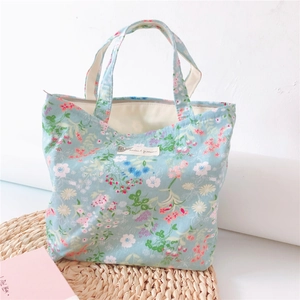 Detail of floral canvas handbag with zipper and top handles on a rustic woven mat