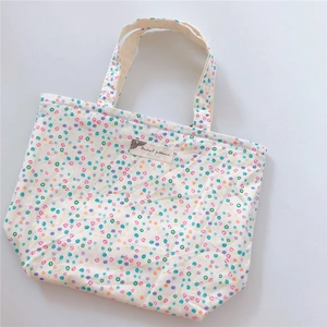Detailed close-up of a white cotton tote bag with colorful polka dots and a vintage label