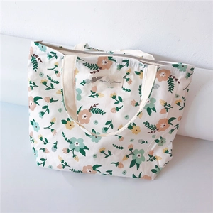 Detailed close-up of a floral canvas tote bag with pink flowers and zipper closure