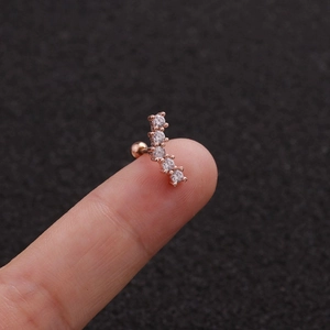 Detailed close-up of a rose gold leaf cartilage stud with zircon stones on a fingertip