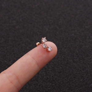 Macro view of rose gold leaf stud earring with clear zircons held on a fingertip