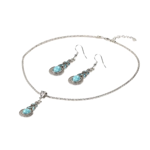 Primo piano di set collana e orecchini in argento con turchese e cristalli blu su sfondo bianco