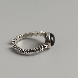 Macro detail of vintage S925 silver ring featuring oval black onyx and textured band