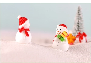 Close-up of miniature resin snowmen with red hats on artificial snow for Christmas decor
