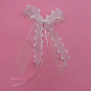 Détail d'un nœud en organza blanc avec dentelle en cœur et de longs rubans fluides
