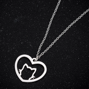 Macro view of silver hollow heart pendant with cat silhouette on glitter background