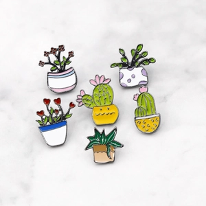 Set of 6 cute cartoon cactus and succulent enamel pins on white marble surface