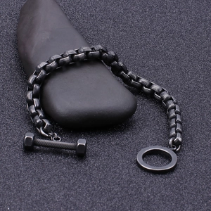 Men's matte black dumbbell bracelet for fitness enthusiasts on dark pebble background