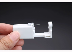 Close-up of a white disposable ear piercing tool with built-in stainless steel stud
