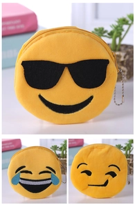Detailed view of plush emoji coin purses with metal chains and zip closures on a desk