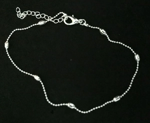 Detail of silver beaded anklet with oval bead accents, lobster clasp and extender chain