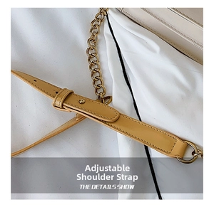 Detail of adjustable khaki leather strap with gold metal buckle and chain on bag