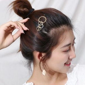 Detail shot of golden multi-loop metal hair clip worn on model with soft lighting