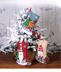 Three burlap Christmas stockings with 3D Santa and reindeer on snowy wood background