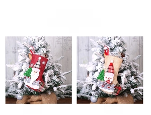 Detail of Santa and Snowman linen stockings with red plaid and sequins on a snowy tree