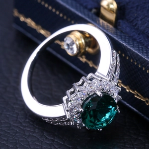 Macro shot of green zircon flower engagement ring with sparkling halo and silver band