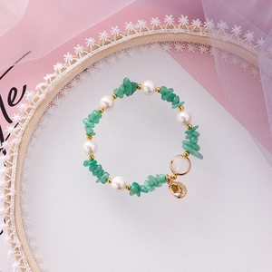 Detail shot of bohemian beaded bracelet featuring green stones, pearls and shell charms