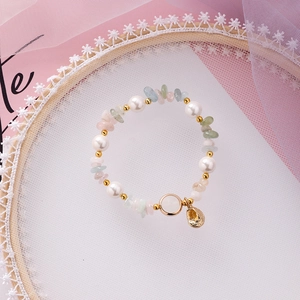 Detail of beaded shell bracelet with pearls and colorful stones on lace background