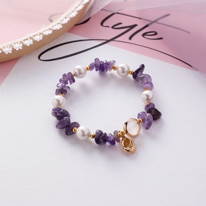 Detail of handmade beaded bracelet with purple stones, white pearls and golden charms