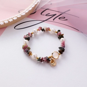Detail of beaded shell and pearl bracelet with colorful gemstones and golden pendants
