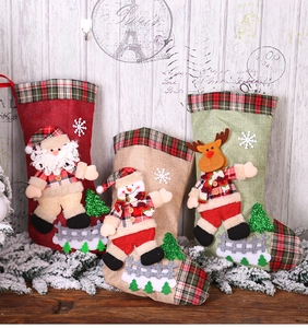 Three burlap Christmas stockings with 3D Santa, Snowman, and Reindeer dolls on wood background