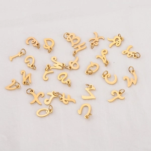 Polished gold stainless steel alphabet pendants with connecting rings on white fabric