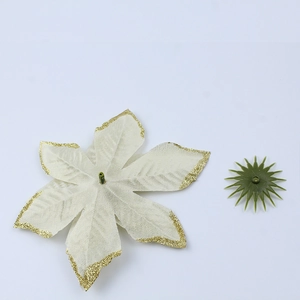 Detail of off-white artificial Christmas flower petal with gold glitter edges and green base