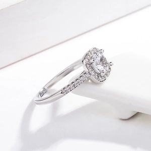 Macro detail of cushion-cut cubic zirconia ring with pavé diamonds on a white stand
