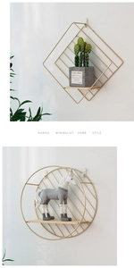 Detalle de estantes de pared nórdicos en metal dorado con formas de rombo y círculo
