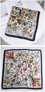 Detail of floral and butterfly print silk scarf with a smooth satin finish and vivid colors