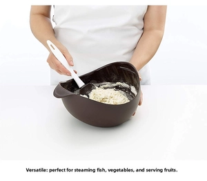 Deep brown multipurpose silicone steaming bowl with white spatula in minimalist kitchen setting