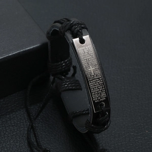 Close-up of black braided leather bracelet with engraved Spanish Lord's Prayer metal plate