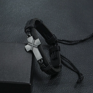 Close-up of black braided leather bracelet with a vintage metal cross charm on gift box