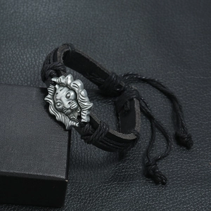 Macro detail of black braided leather bracelet featuring a silver lion head metal charm