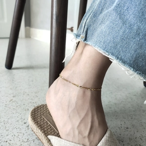 Detail view of 925 sterling silver minimalist anklet worn on model's ankle in gold finish