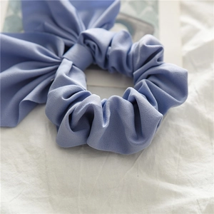 Close-up of a light blue knotted bow scrunchie with fine twill texture and elastic band